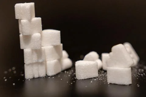 Close up of a leaning stack of sugar cubes and heart shaped sugar pieces on a Stock Photos
