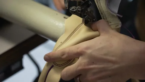 Close up of a leather baseball glove seam being stitched on an industrial Stock Footage 340277549