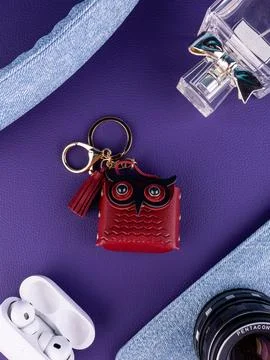 Close-up of a leather owl bag charm attached to a burgundy handbag. Stylish f Photos