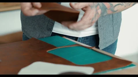Close-up. A leather purse maker at work in a workshop. the man's hands hold a cu Video stock 299717001