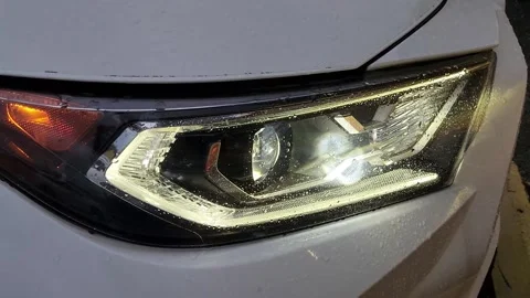 Close-up of LED low beam headlight on white car front Stock Footage 327067294