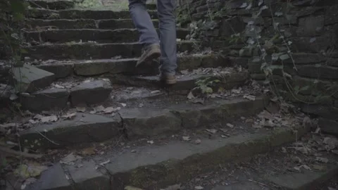 Close up of legs with brown hiking boots walking up an old stone staircase Stock Footage