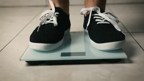 Close-up of legs getting on electronic weight and controlling their healthy Stock Footage 150260494