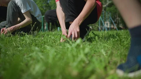Close-Up of Legs on Grass with Two People Squatting and Adjusting Shoes Видео 286790701