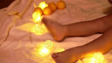 Close-up legs of kid boy . Garlands lights and tangerines on background. Stock Footage 220868406