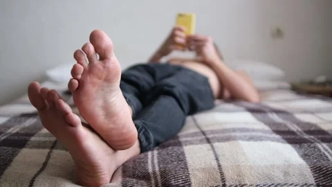 Close-up of the legs. The man is lying on his back. Uses the phone. Selective fo Stock Footage 147384181