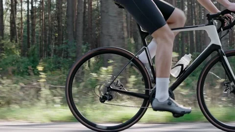 Close-up of the legs of a man riding a road bike in a sunny forest Vídeo Stock 166173161