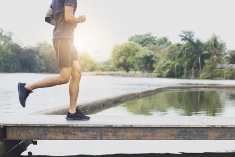Close up legs of man running and exercising on wood bridge in park Stock Photos