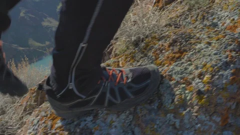 Close-up of the legs of a man walking along the edge of a cliff 스톡 동영상 130109210