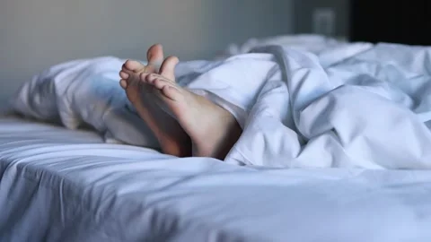 A close-up of the legs of a sleeping small child on a large white bed Stock Footage 274300060