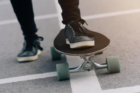 Close-up legs stand on a longboard while riding on the road in the city. The  Stock Photos