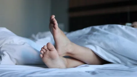 Close-up: the legs of two children enjoying a nap on a large bed in a calm  Stock Footage 270943176
