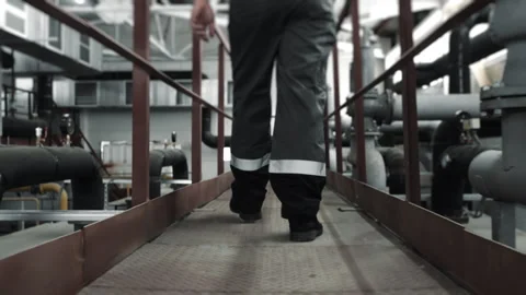 Close-up of the legs of a uniformed worker walking through a factory. Stock Footage 306816315