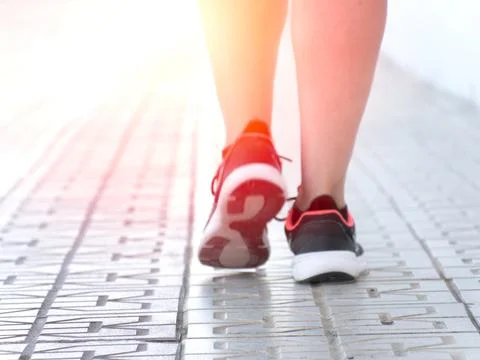 Close-up of legs walking on a paved path Stock Photos