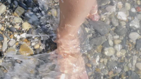 Close-up of legs walking on a pebble beach Stock Footage 288860369