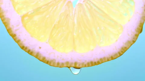 Close-Up of Lemon Slice with Dripping Drops on Turquoise Background Video stock 330604075