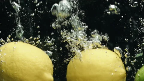 Close-up of lemons and limes falling into the water in slow motion. Stock Footage 170462659