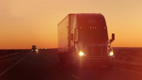 CLOSE UP LENS FLARE Semi trucks transporting goods on highway at morning sunrise Stock Footage 79082428