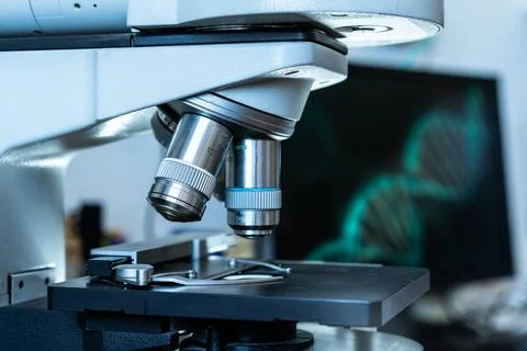 Close up of the lenses of a microscope with an dna image on the background in Foto stock