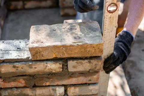 Close-up of leveling bricks during construction of brick structure using spirit Stock Photos