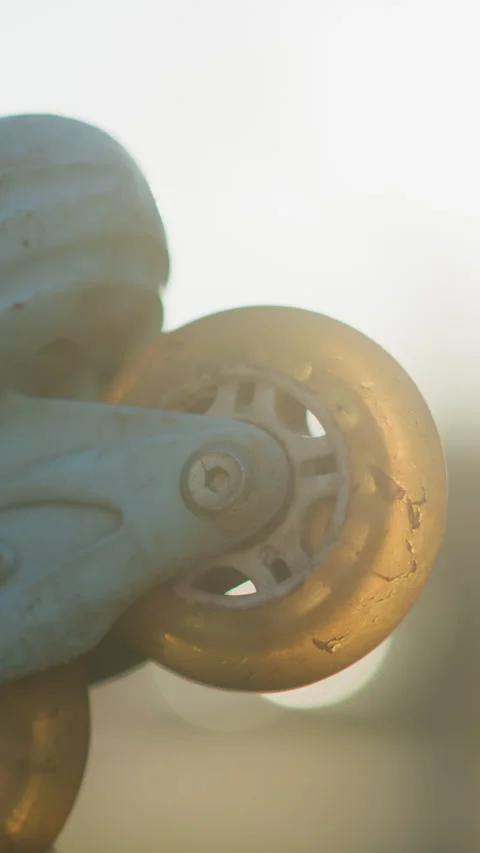 Close-Up of Light Blue Rollerblade Wheels Held in Warm Sunlight at Park Stock Footage 310492186
