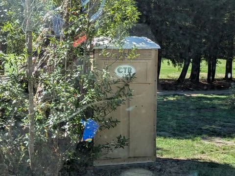Close-up of a light brown CTR porta potty near green grass at a golf course Stock Photos