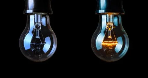 Close up light bulb and one glowing bulb on black background Stock Photos