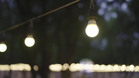 Close-up of a light bulb hanging under an umbrella outside a house at night. Stock Footage 252072028