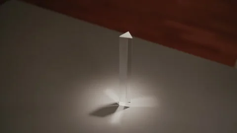 Close-up of light refracting through triangular glass prism, splitting into Stock Footage 312329785