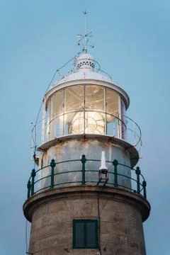 Close up of lighthouse beacon lighting up at sunset and blue background Foto stock