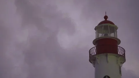 Close-up of a lighthouse illuminating the coastline on a cloudy, stormy day  Stock Footage 318298034
