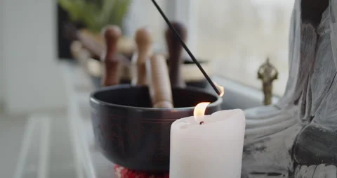 Close-up of lighting an incense stick from a candle standing near singing bowl Stock Footage 156769283