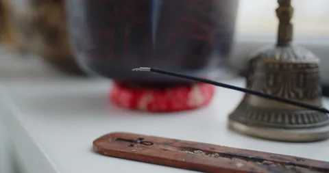 Close-up of lighting an incense stick from a candle standing near singing bowl Stock Footage 156769351