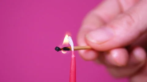 Close up on Lightning a candle on a birthday cake. Close up on burning pink or Stock Footage 163309161