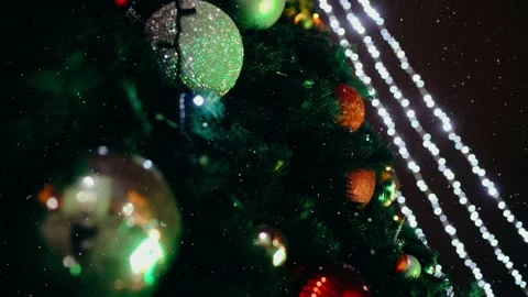 Up close the lights of a fir tree decorated with globes while it is snowing Stock Footage 145127170