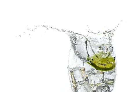 Close up of lime slice dropped in water glass. Stock Photos