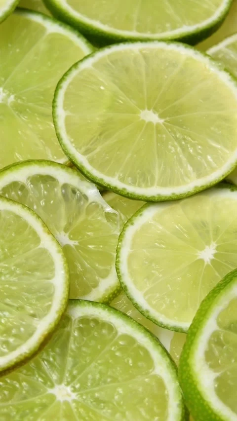 Close-up lime slices rotate in a vertical frame, revealing fresh citrus texture Stock Footage 346672238