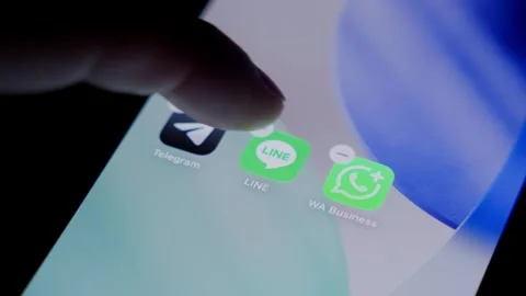 Close-up of the LINE app being deleted from a smartphone home screen in a dark Stock Footage 337240055
