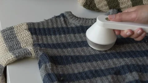 Close-up of lint remover cleaning old sweater fabric to prepare garment for Video stock 331010474