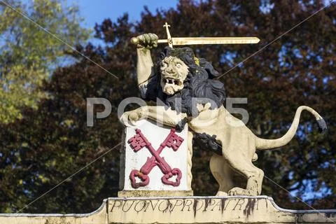 Close-up of lion sculpture with sword on top of monument with trees in the backg Stock Photos