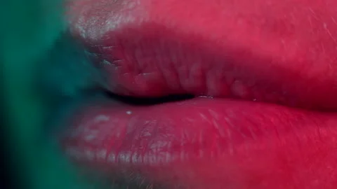 Close up of lips blowing. Colourful lighting macro shot. High quality audio. Stock Footage 144787892