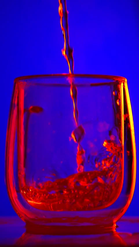Close up of Liquid Being Poured into Glass with Colorful Lighting Stock-Footage 332542771