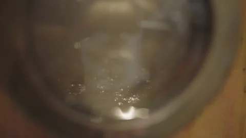 Close up of liquid bubbling inside a copper gin still pot at distillery Stock Footage 150798990