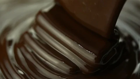 Close up of liquid dark chocolate pouring into a large vat of chocolate Stock Footage 126764042