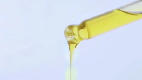 Close up of liquid oil drop from lab pipette on white background Stock Footage 300014676