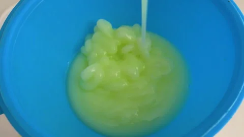 Close-up. Liquid soap is poured into a jar through a plastic watering can. Stock Footage 336557111