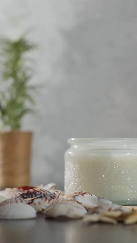 Close up of lit candle with seashells arranged around it on flat surface soft Stock Footage 345724049