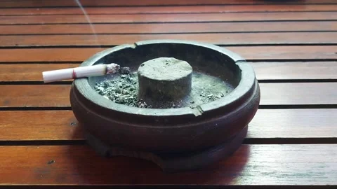 Close up of a lit cigarette burning in a stone ashtray. Video stock 319463842