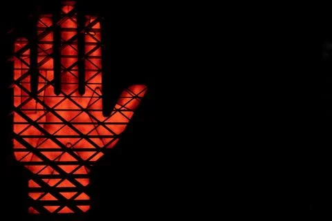 Close up of a lit up do not walk hand signal with a black background Stock Photos