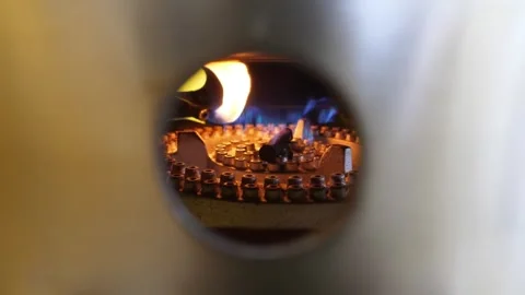 Close-up of a lit gas burner inside an industrial furnace with blue and orange f Stock Footage 345692442